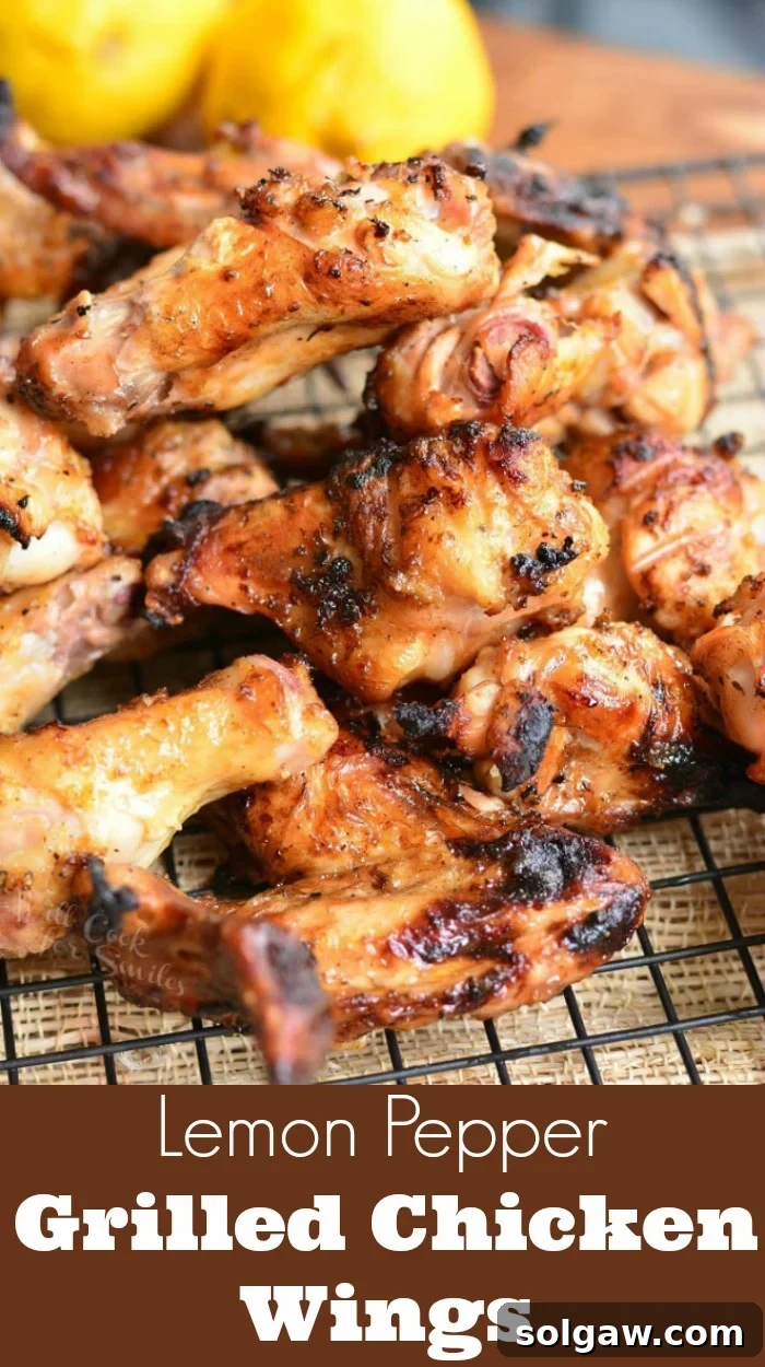 Perfectly grilled chicken wings stacked on a cooling rack with fresh lemons