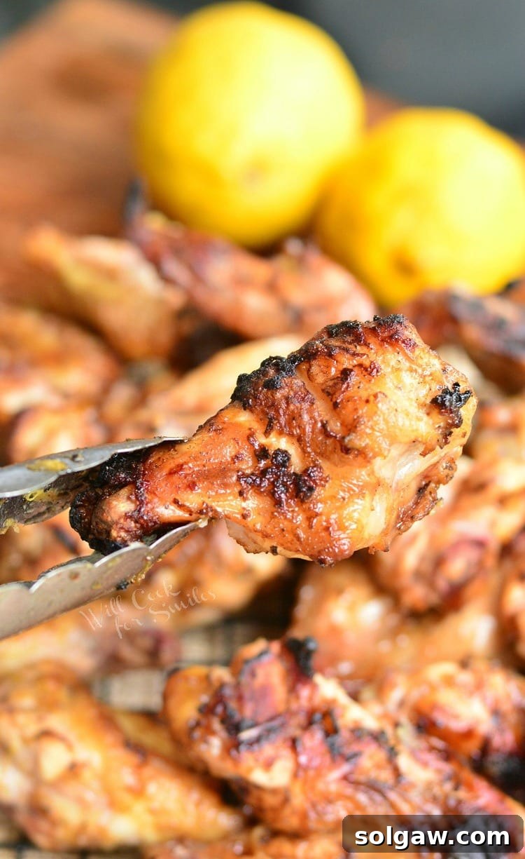 Tongs holding a perfectly grilled lemon pepper chicken wing