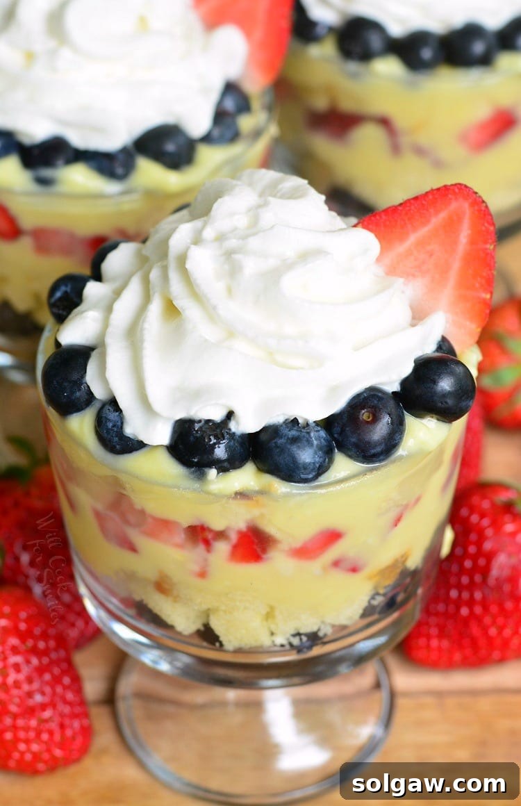 Easy Coconut Berry Trifle in a glass serving bowl on a cutting board with a strawberries