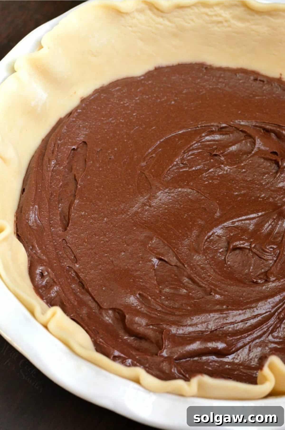 The fudgy brownie layer evenly spread in a pie shell, ready for the pecan topping and filling.