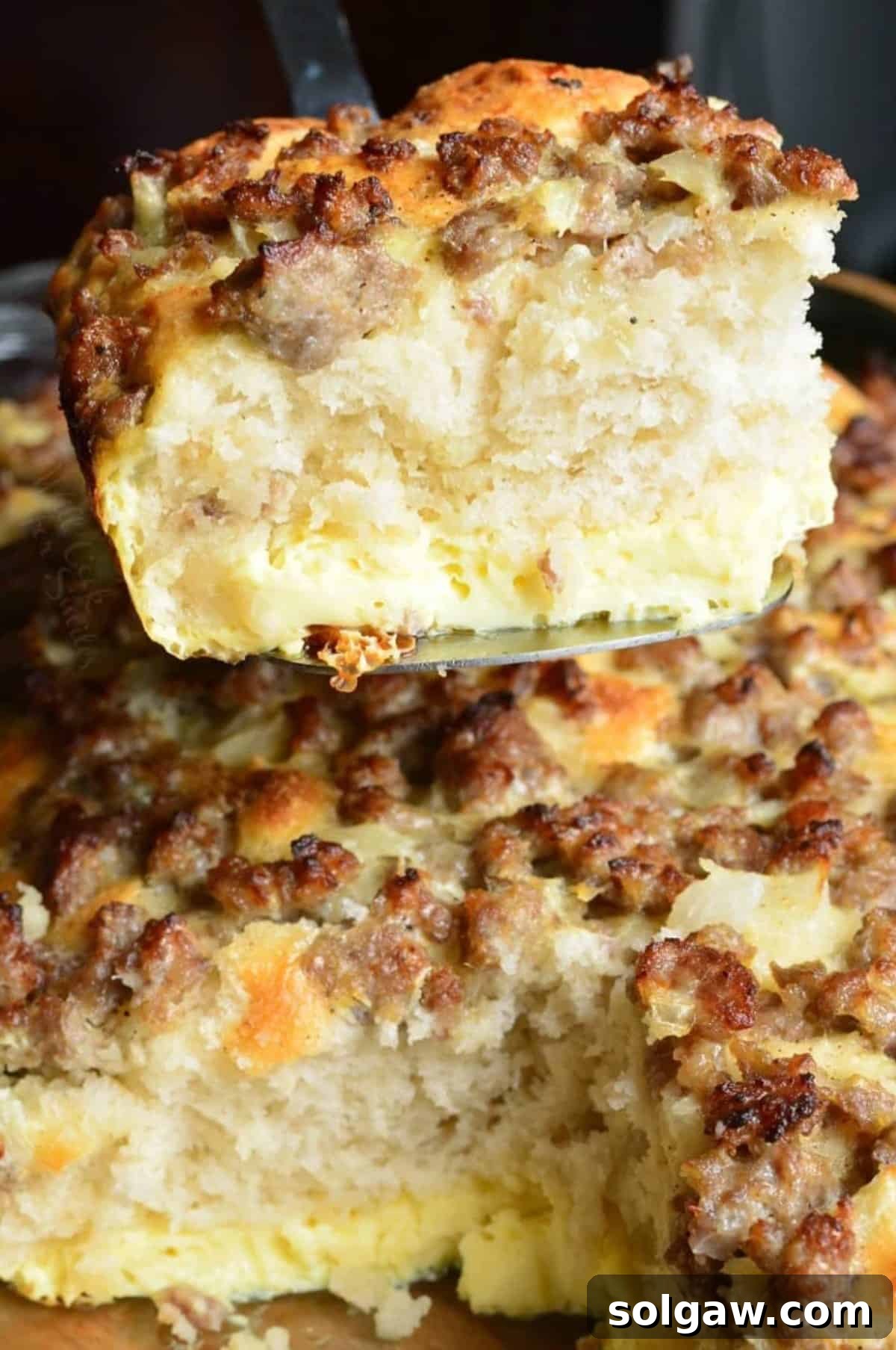 Hearty Sausage & Egg Breakfast Bake 6 A spatula lifting a piece of golden-brown sausage breakfast casserole from the dish.