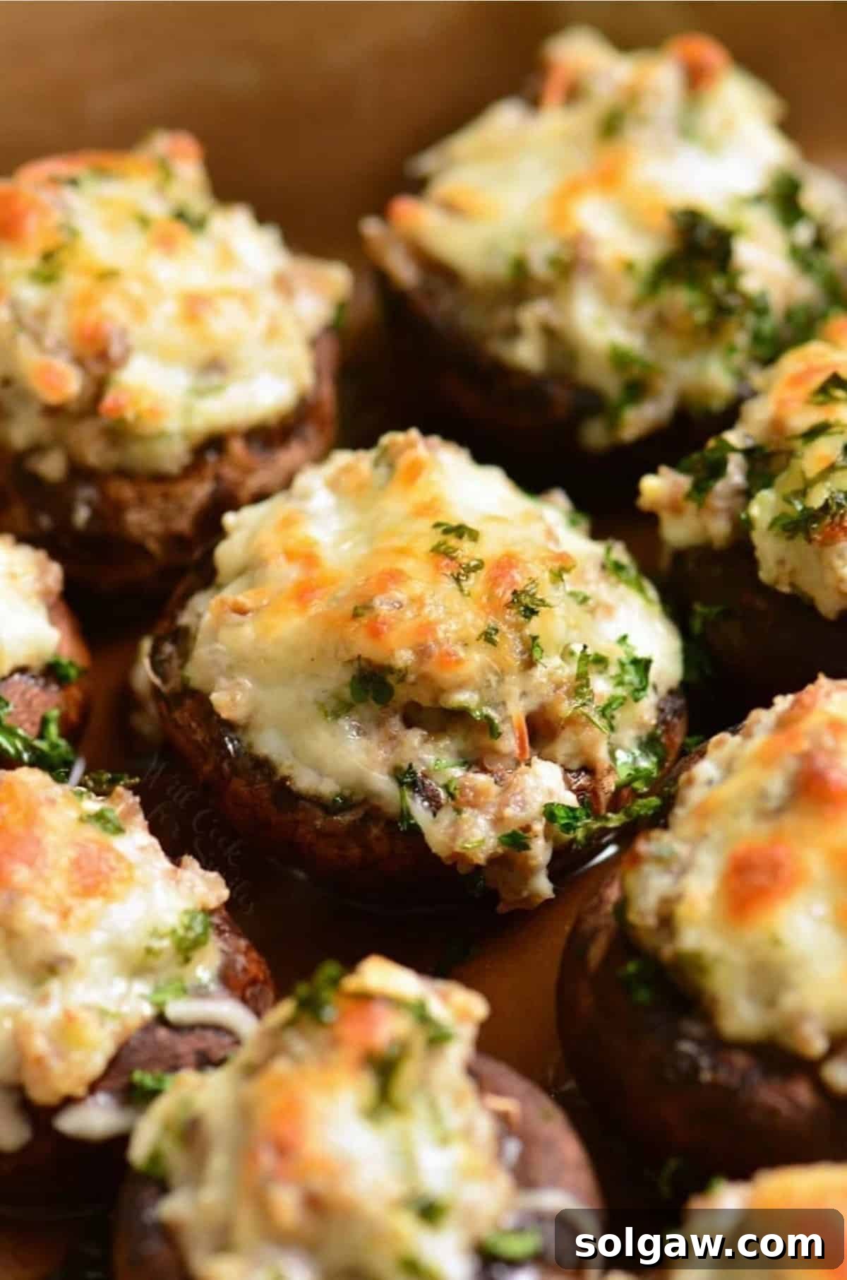 Sausage stuffed mushrooms garnished with fresh parsley in a baking dish, ready to be served.