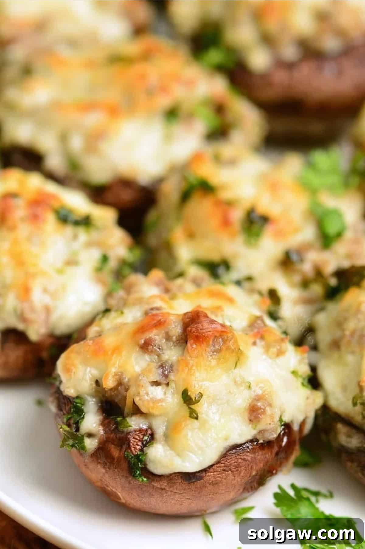 Beautifully baked sausage stuffed mushrooms garnished with fresh parsley on a serving platter.