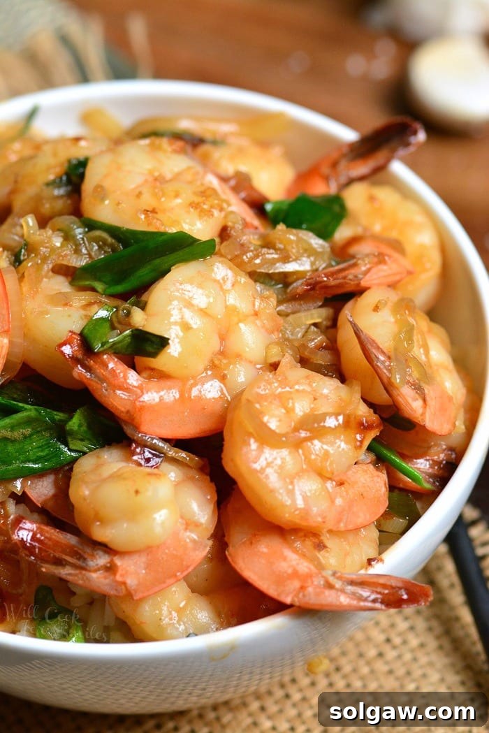 a white bowl filled with rice and topped with juicy shrimp.