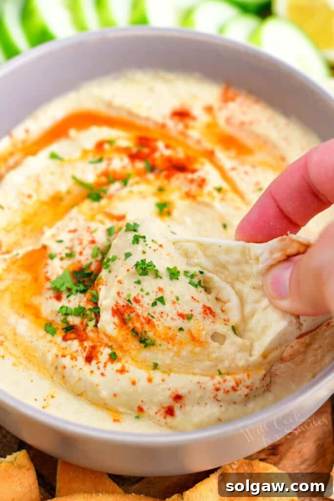 A piece of naan is being dipped into hummus.