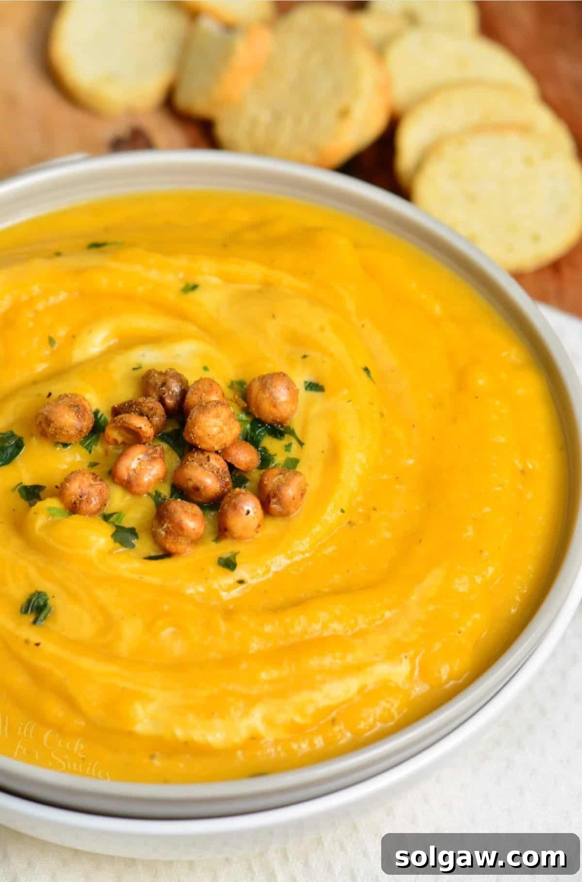 Creamy Instant Pot Butternut Soup 9 butternut squash in a bowl with chickpeas on top and bread slices in the background.