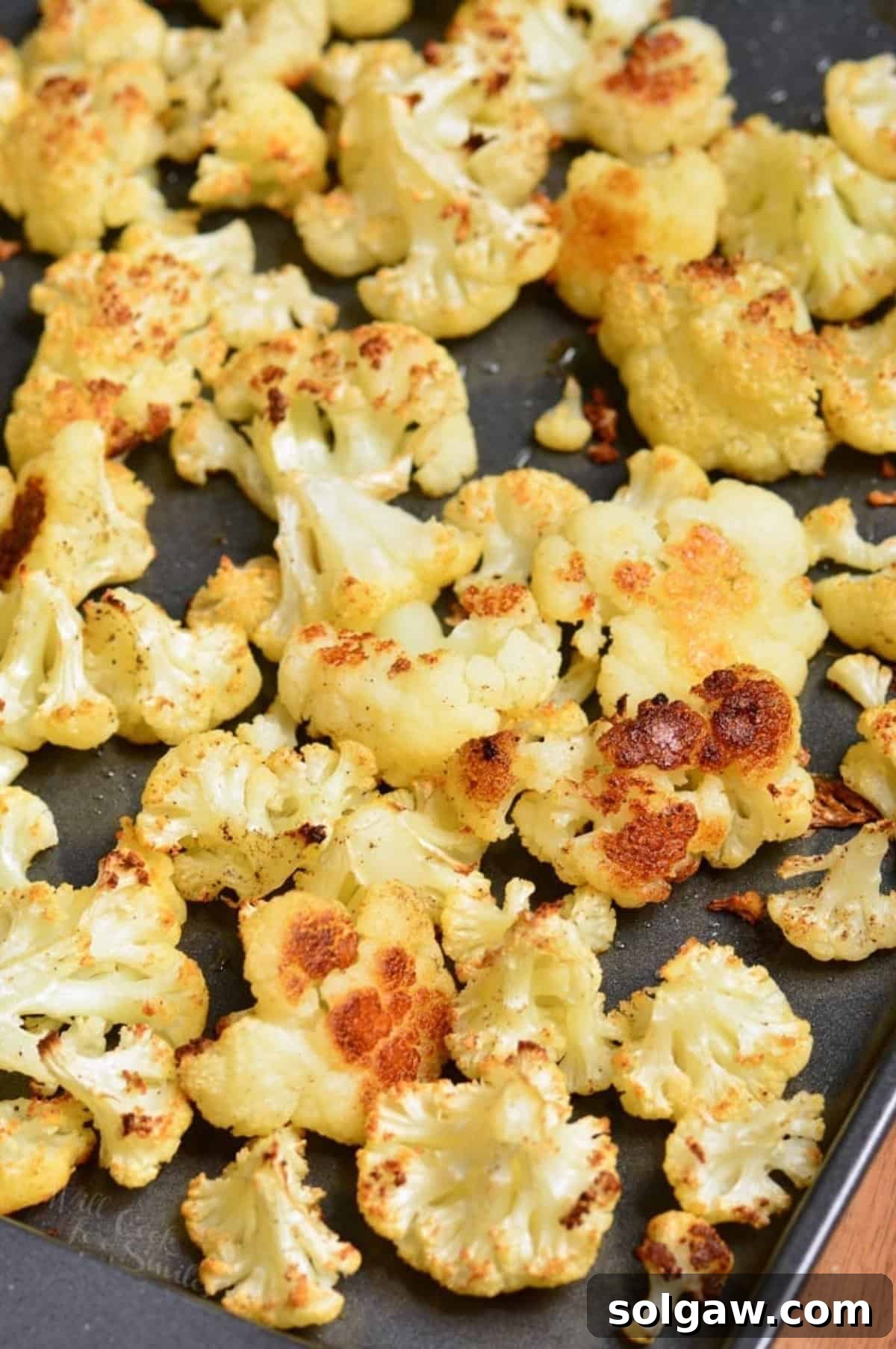 Roasted cauliflower florets on a baking sheet, golden brown and perfectly cooked.