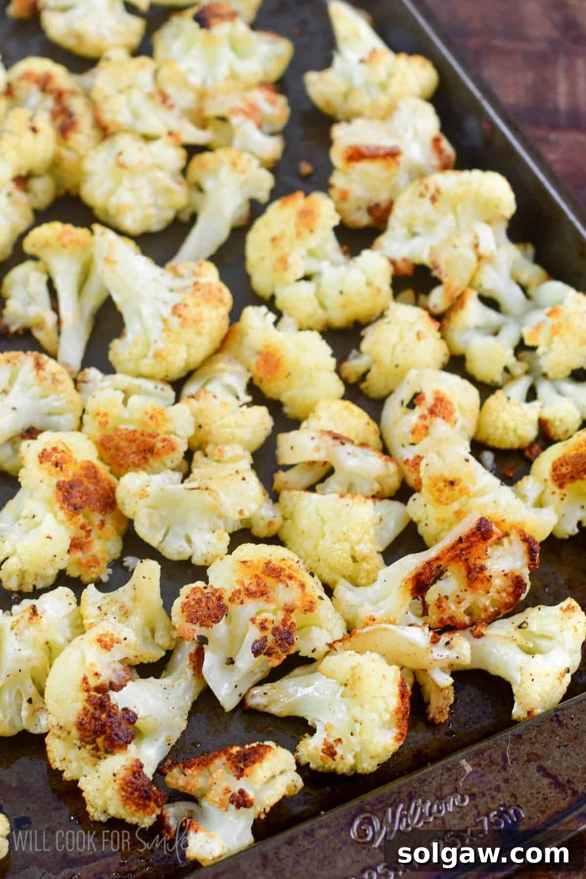 Roasted cauliflower florets spread on a baking sheet, ready to be served.