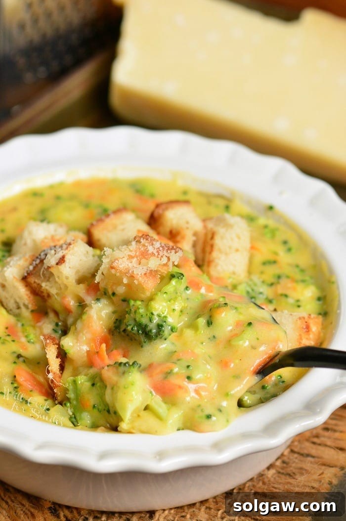 creamy and cheesy broccoli cheese soup with lots of broccoli and carrots in a bowl.