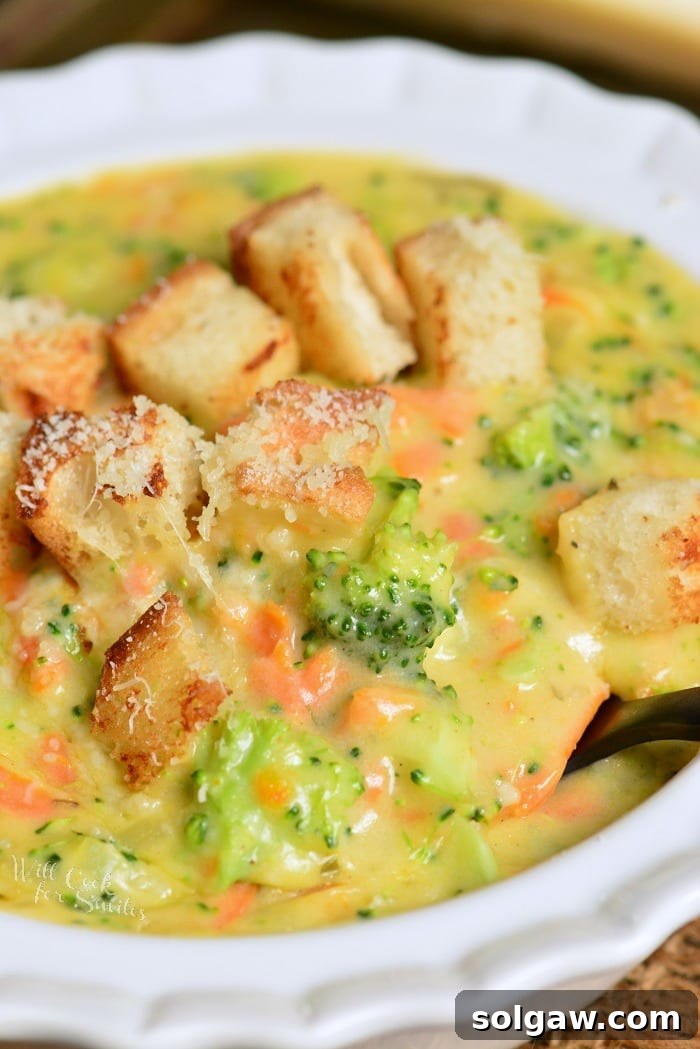starting to spoon out some broccoli cheese soup topped with croutons.