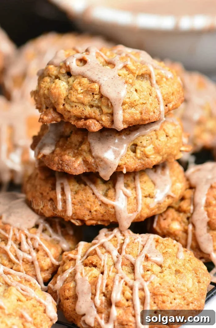 Stacked soft and chewy Cinnamon Oatmeal Cookies on a rustic wooden surface, highlighting their texture and cinnamon glaze.