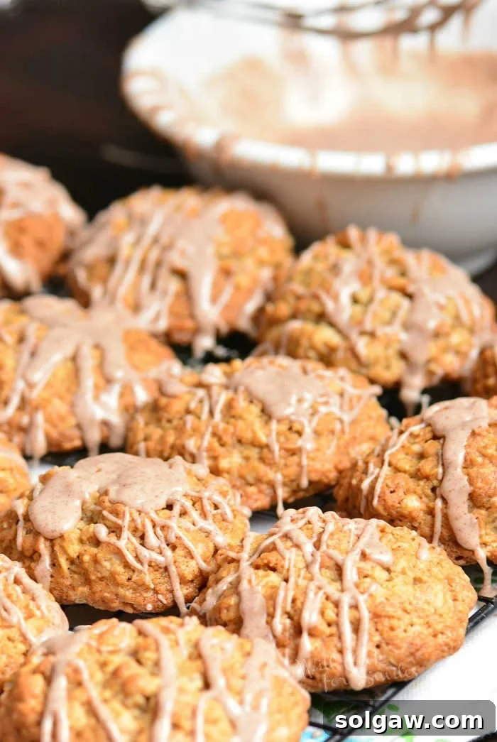 A top-down shot of a stack of Cinnamon Oatmeal Cookies with a drizzle of glaze, presented on a round white plate.