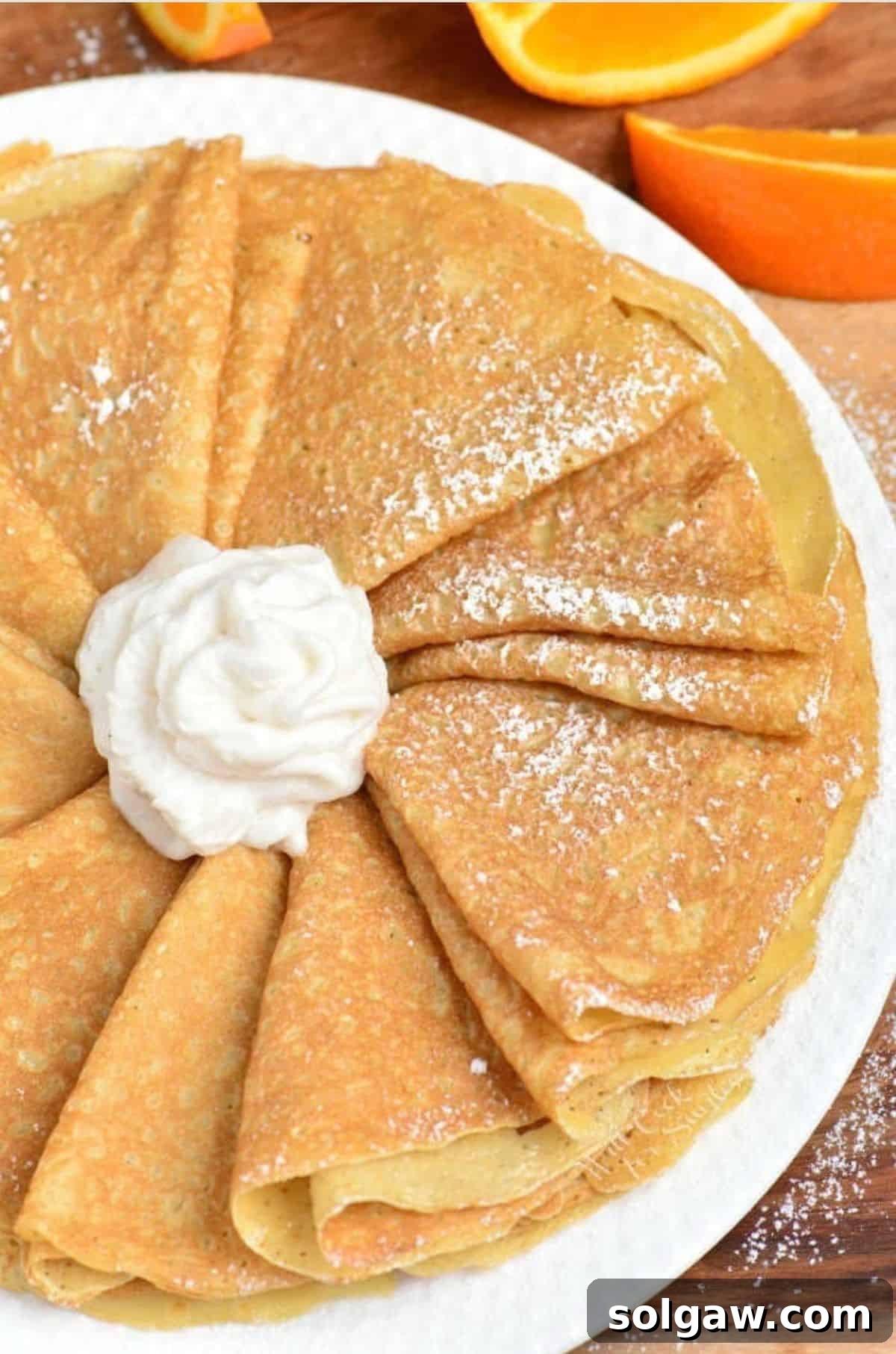 The Art of Perfect Crepes 6 Folded crepes arranged artfully on a platter with a dollop of whipped cream in the middle, showcasing their elegant presentation.