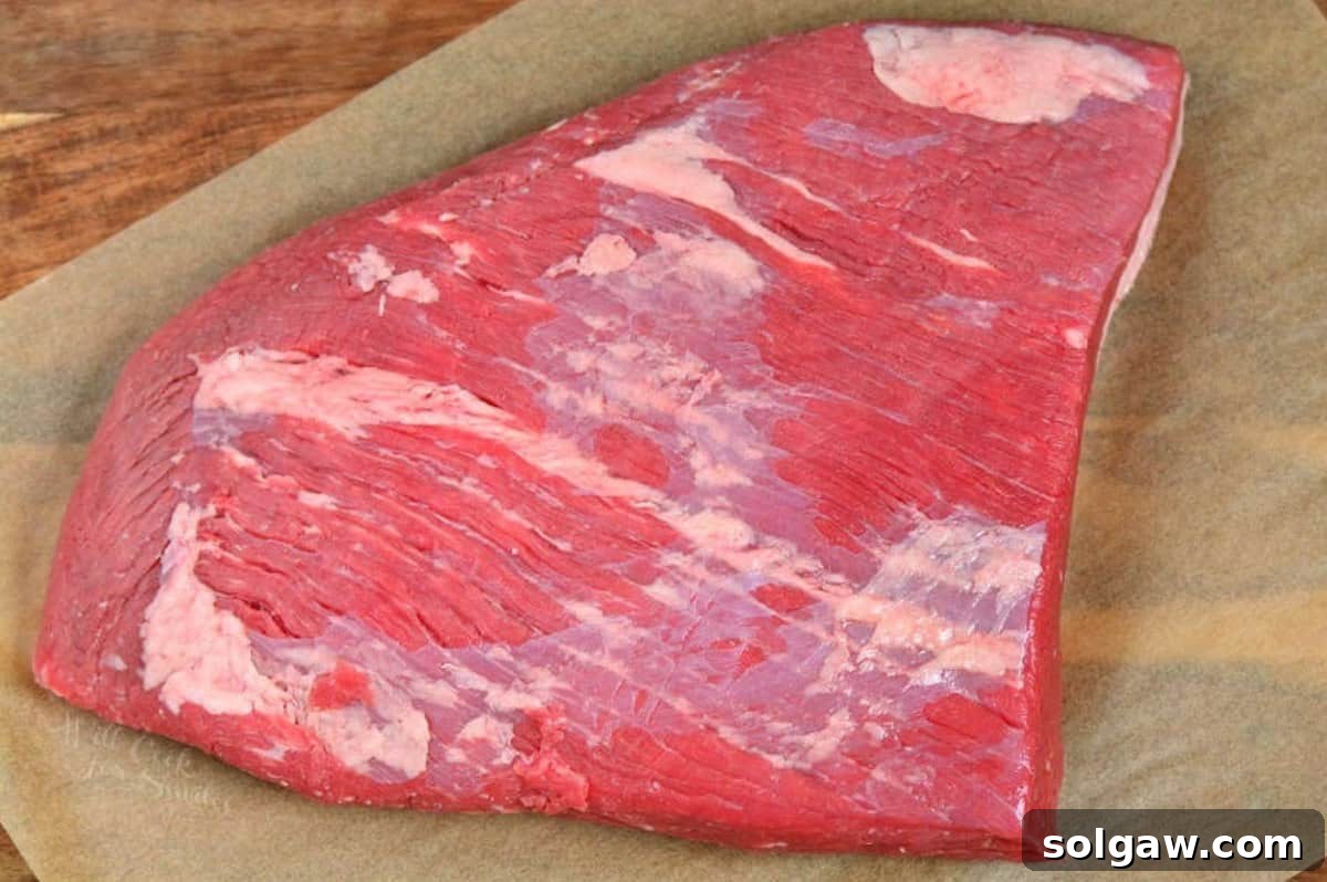 uncooked flat cut of a beef brisket laying on the parchment paper. 