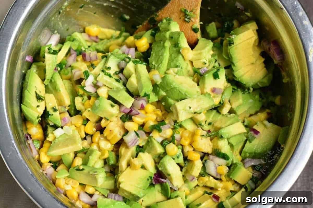 Vibrant Avocado and Sweet Corn Salad 3 A close-up shot of fresh avocado, corn kernels, and finely diced red onion in a mixing bowl, ready to be combined for a delicious avocado corn salad.