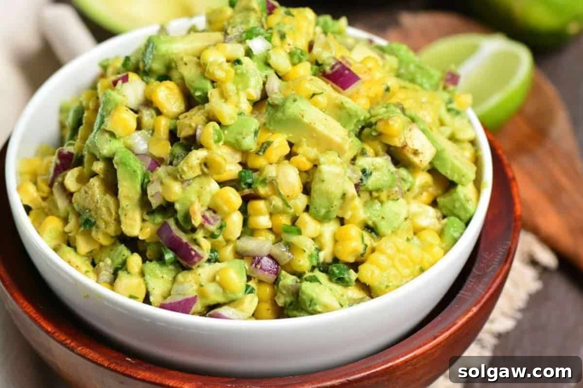 Vibrant Avocado and Sweet Corn Salad 5 Avocado Corn Salad presented in a small bowl, artfully placed atop a larger wooden bowl, ready to be served as a delightful side or dip.