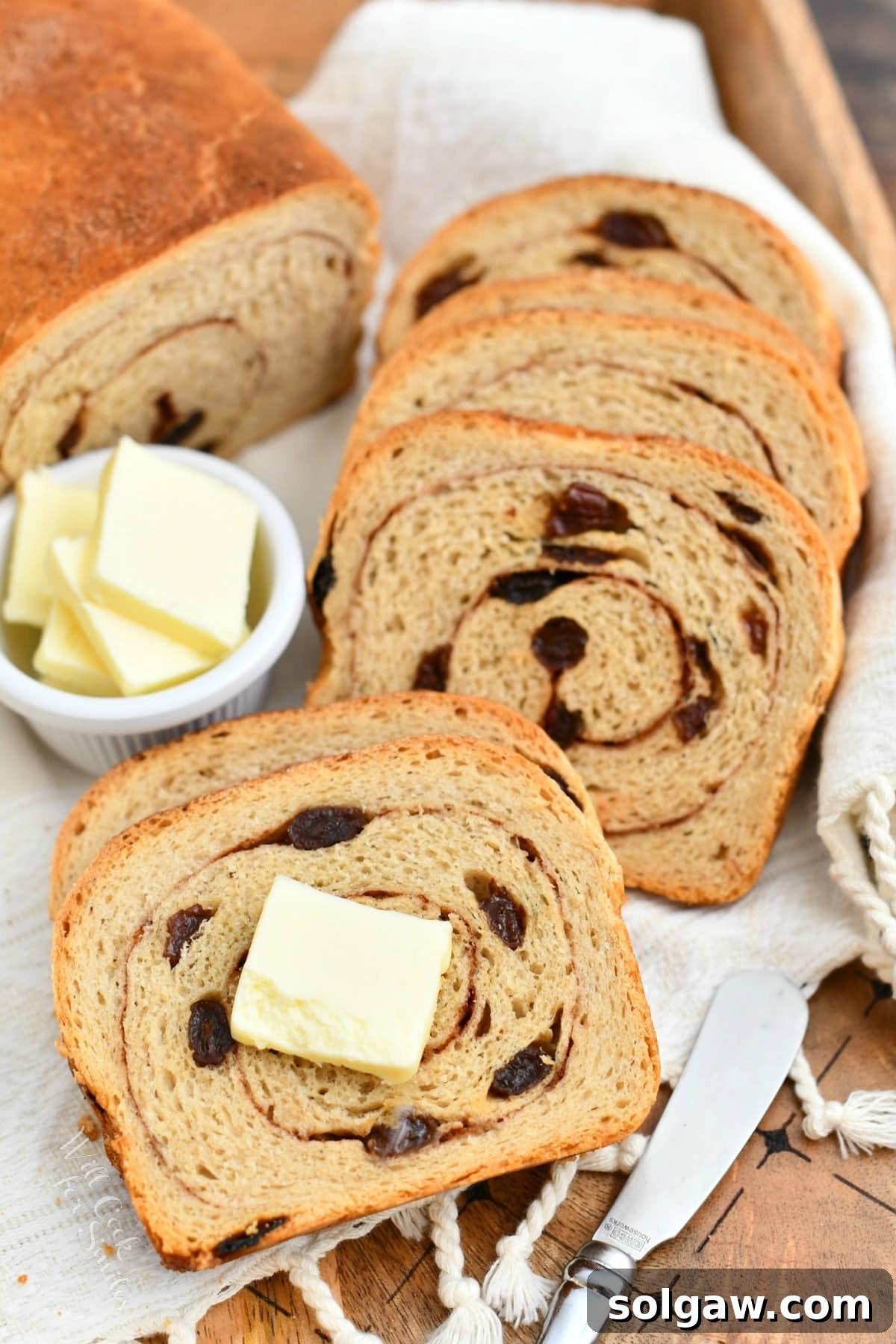 slices of freshly baked cinnamon swirl bread next to tabs of butter in white dish