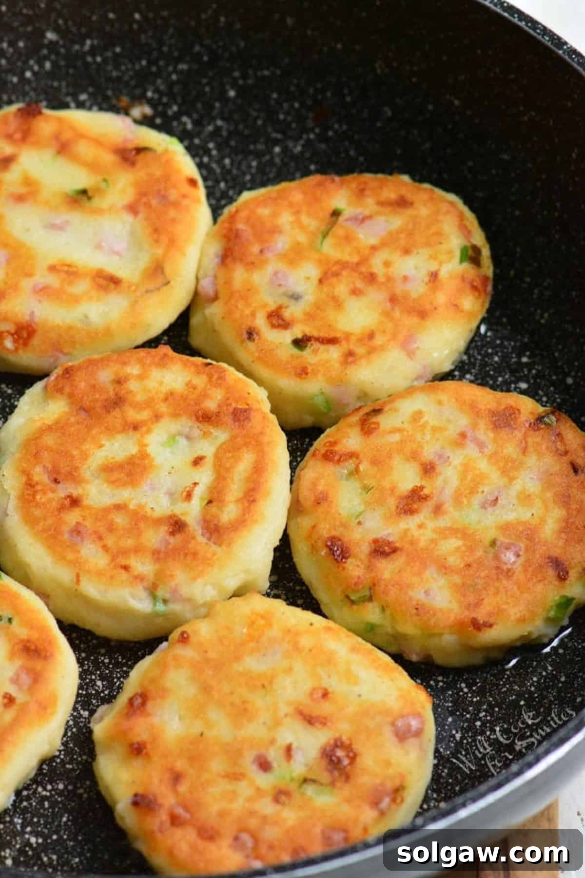 Savory Ham and Cheese Potato Patties 5 several mashed potato cakes cooking in the pan.