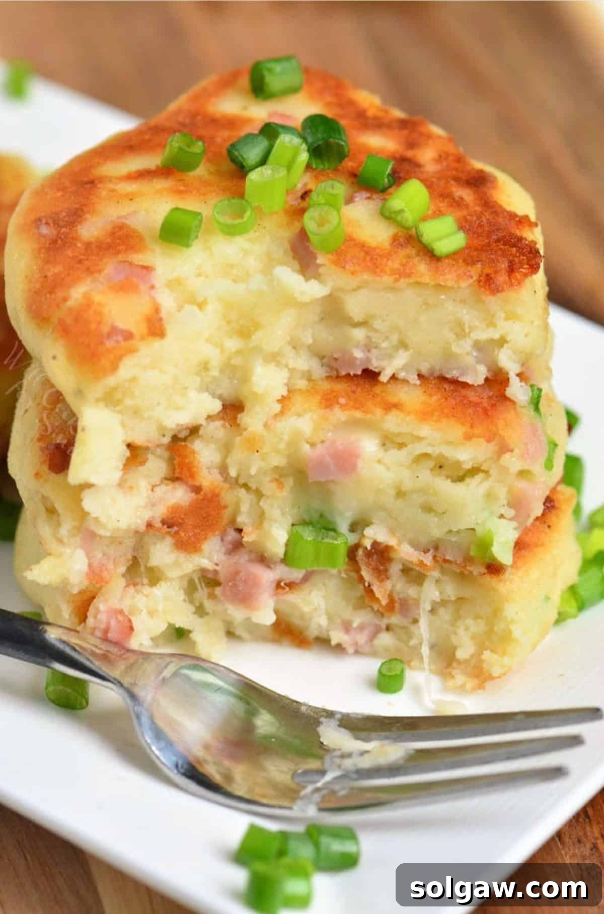 Savory Ham and Cheese Potato Patties 6 three ham and cheese mashed potato cakes stacked and some cut out with a fork.