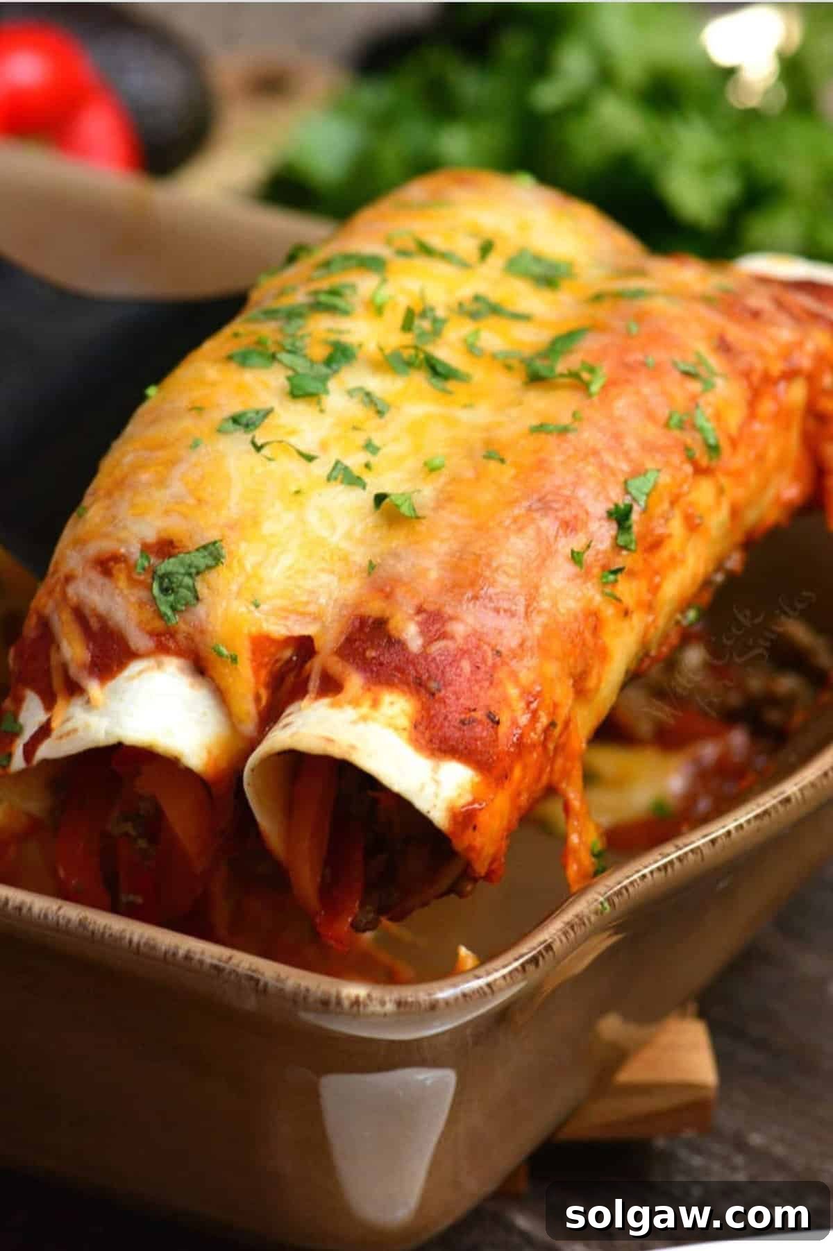 A close-up shot of two golden-brown, cheesy beef enchiladas being gently removed from a hot baking dish with a spatula, steam rising, highlighting the perfectly melted cheese and rich sauce.