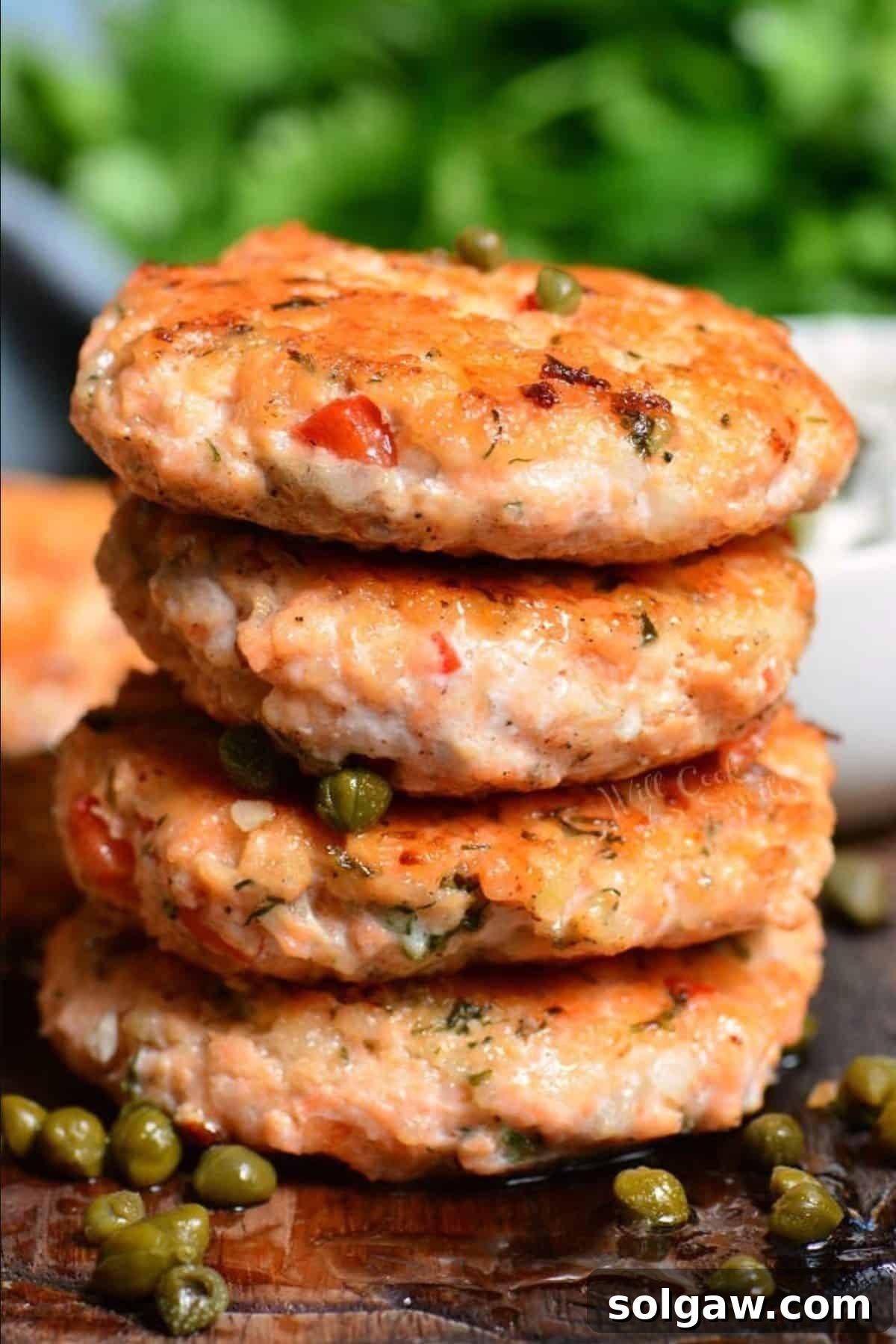 stack of four salmon patties with capers around and on top.