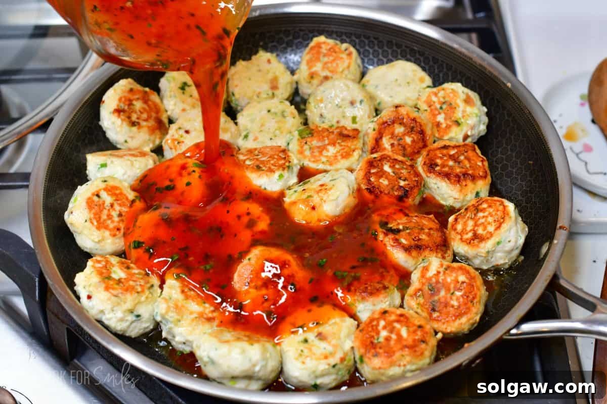 Sweet Chili Glazed Turkey Meatballs 6 Pouring Thai sweet chili sauce mixture over meatballs that are in a pan.