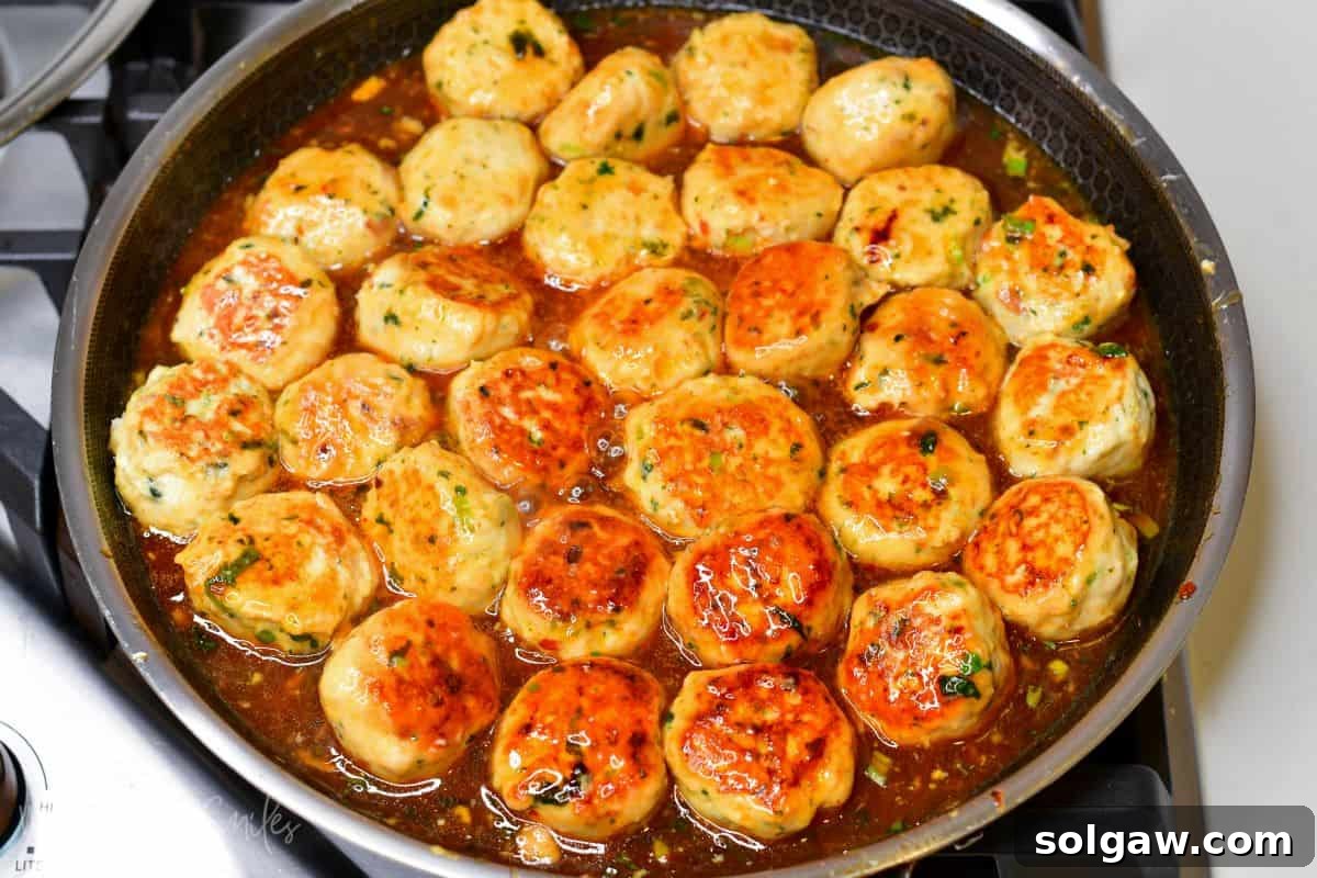 Sweet Chili Glazed Turkey Meatballs 7 Thai turkey meatballs cooking in the sauce in a pan.