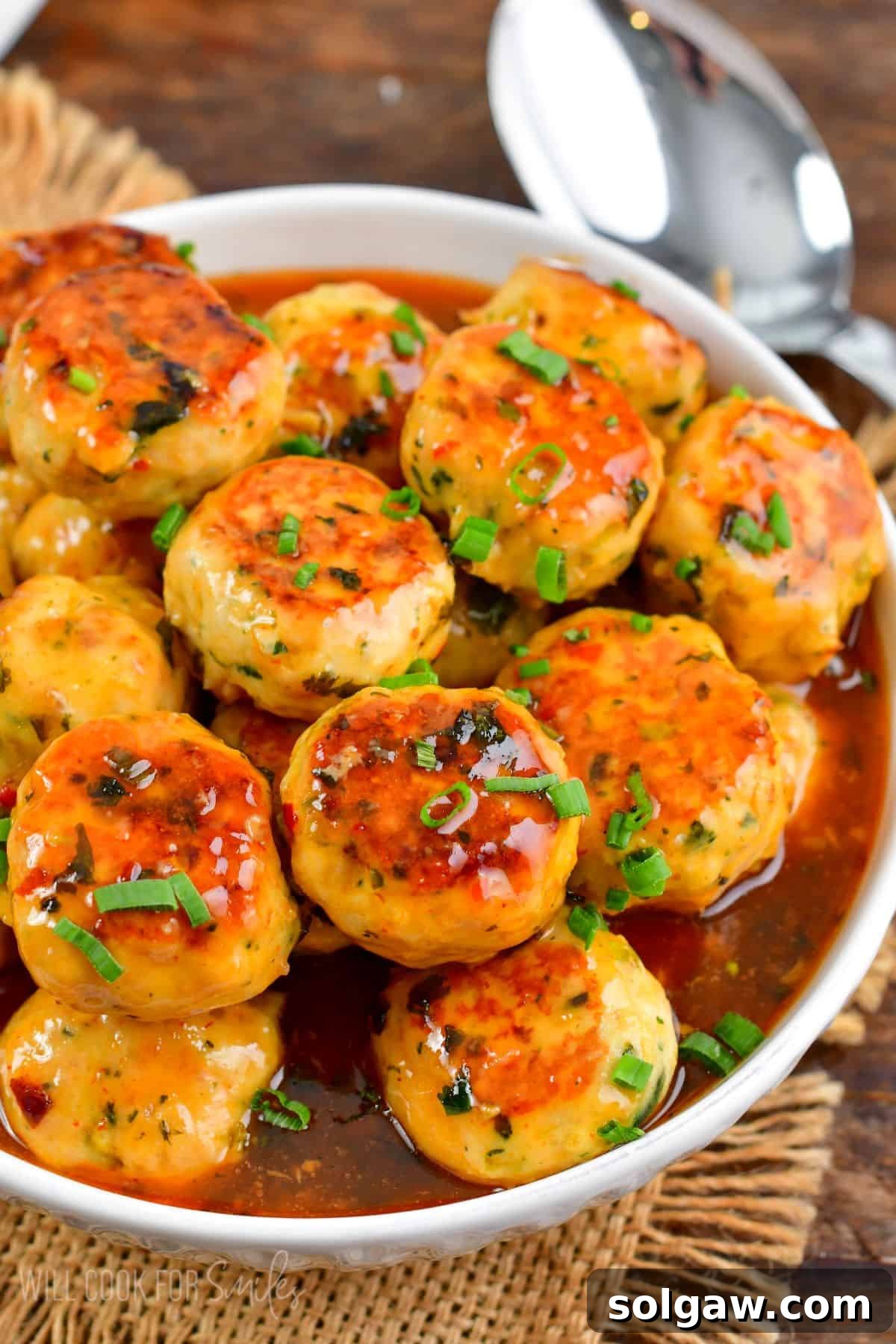 Sweet Chili Glazed Turkey Meatballs 9 Thai Sweet Chili Turkey Meatballs in a bowl with a spoon to the right on a wood table.