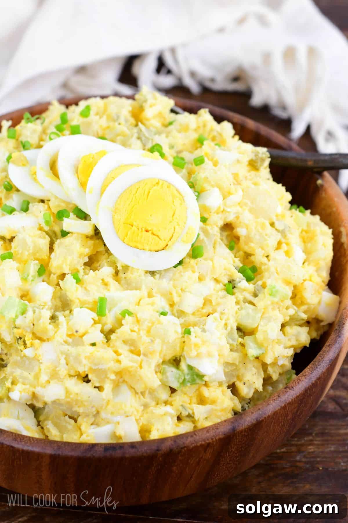 Homestyle Southern Potato Salad 2 a wooden bowl filled with mustard and pickles potato salad.