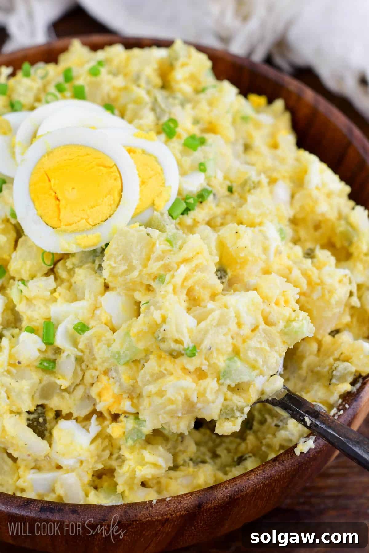 Homestyle Southern Potato Salad 6 scooping out some southern potato salad from the bowl and sliced egg on top.