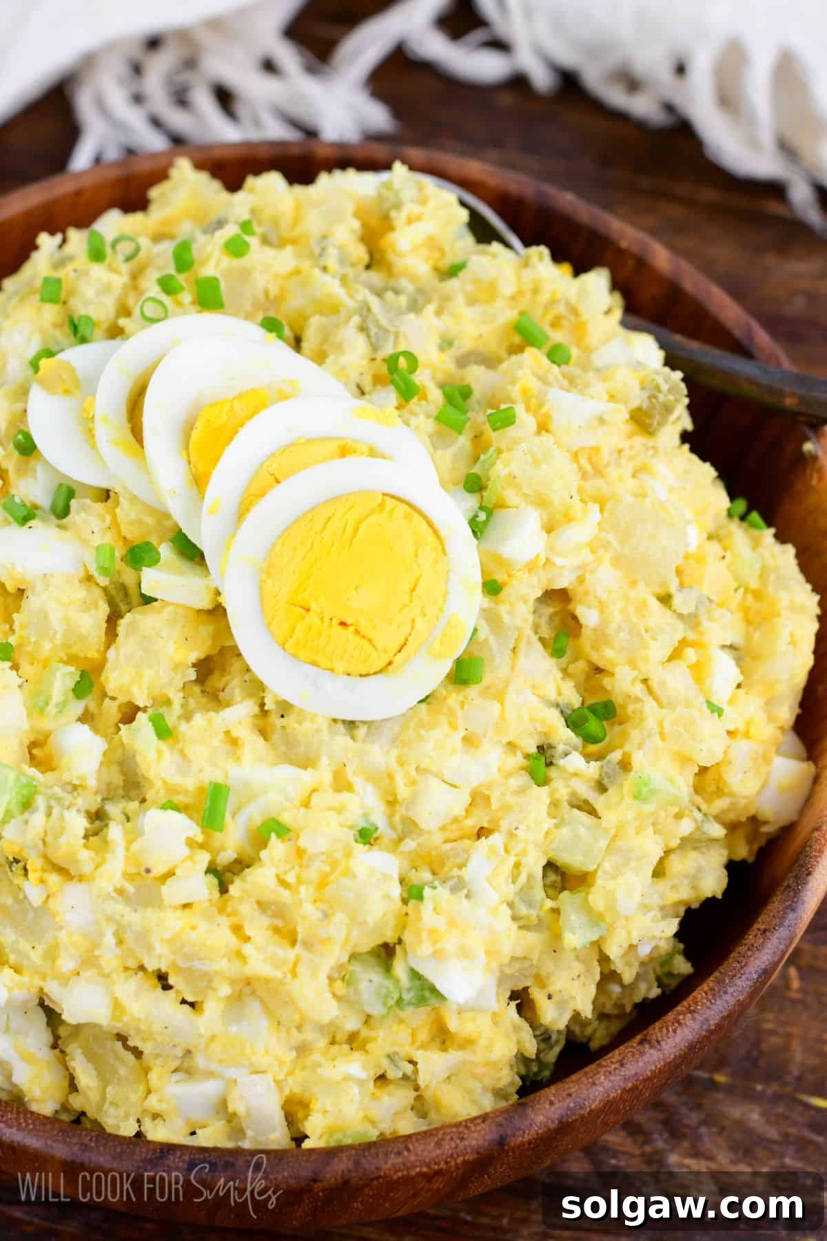 potato salad with eggs, pickles, and creamy mustard sauce in a bowl topped with egg.