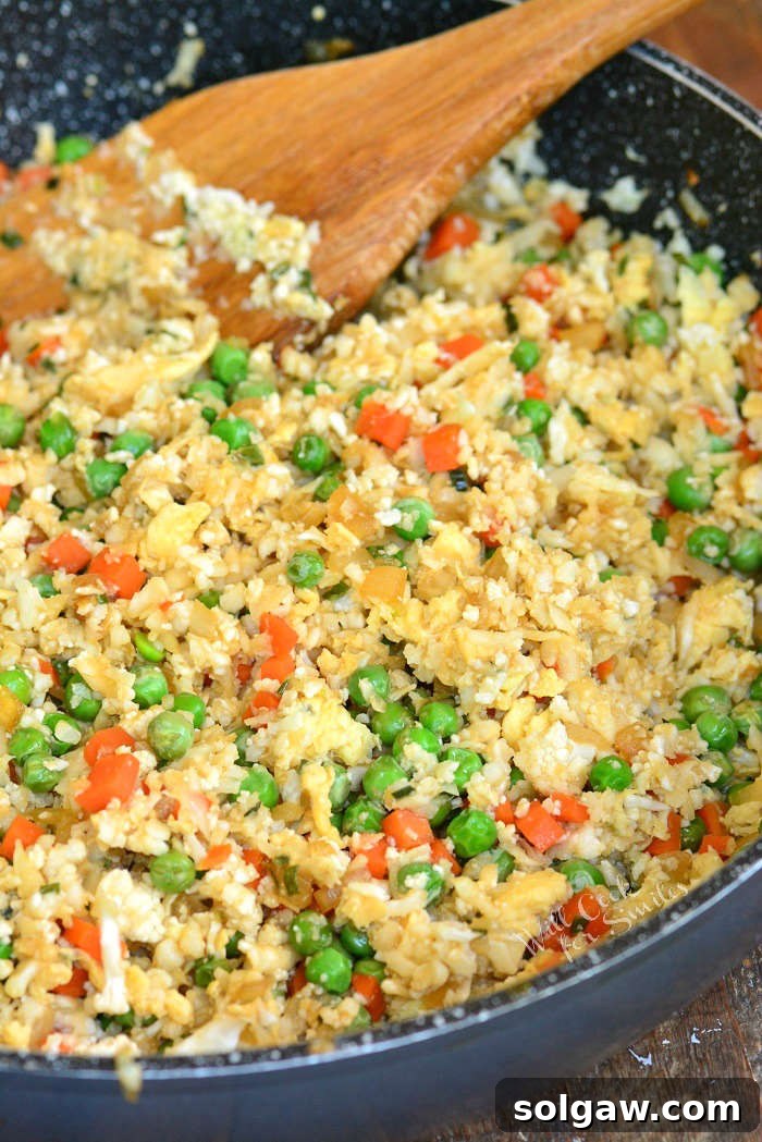 Cauliflower fried rice in a pan with a wooden spoon 