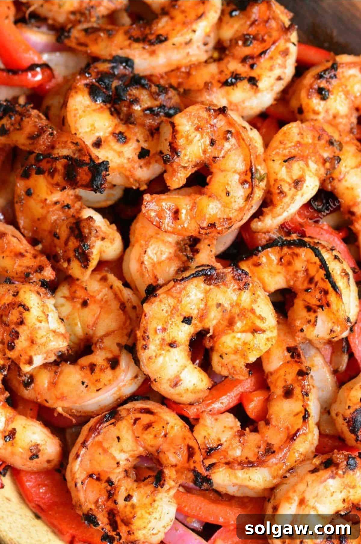 Zesty Cajun Grilled Shrimp & Garden Vegetables 8 A generous serving of cooked Cajun grilled shrimp, glistening with marinade, presented on a vibrant bed of grilled bell peppers and onions