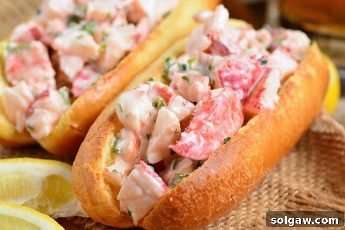 hot dog bun filled with lobster mixture and one on background.