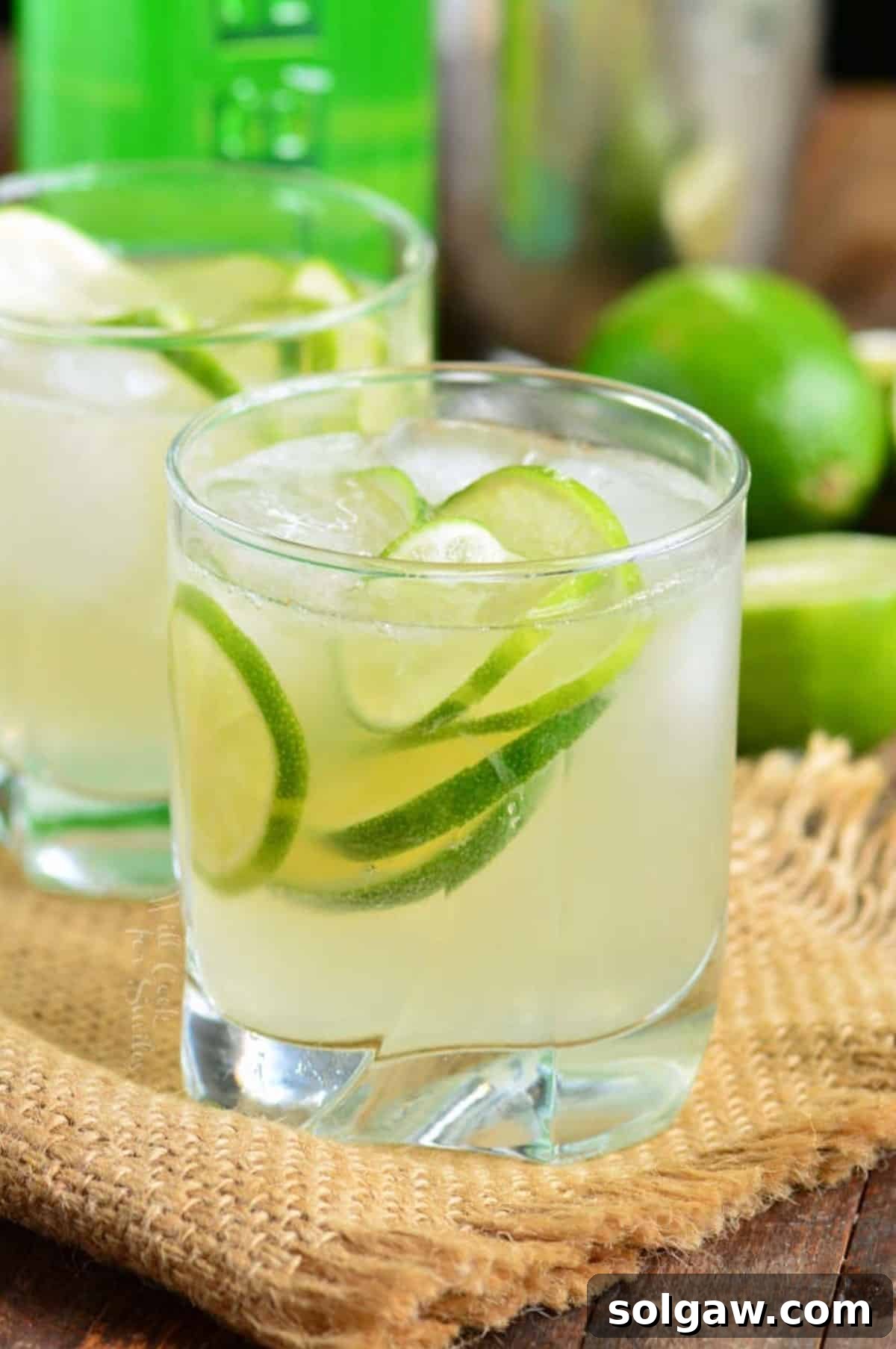 A Caipirinha cocktail served in a short glass with ice and lime wedges.