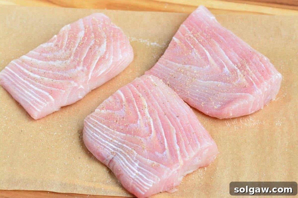 Golden Pan Seared Mahi Mahi with Bursting Tomato Basil 3 three seasoned uncooked filets of mahi mahi on the parchment paper.