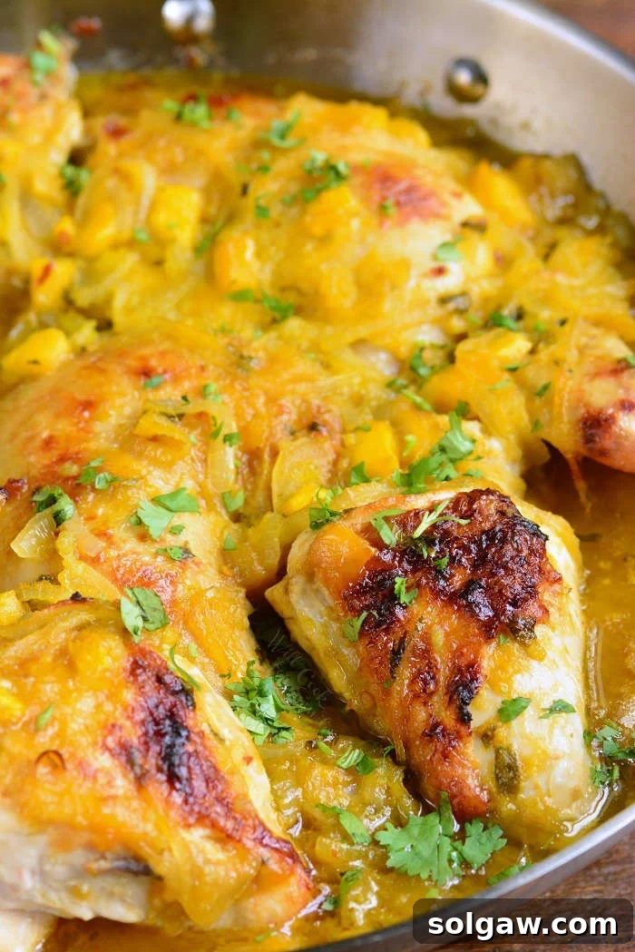 Perfectly baked chicken with vibrant mango sauce, garnished with cilantro, fresh out of the oven in a skillet