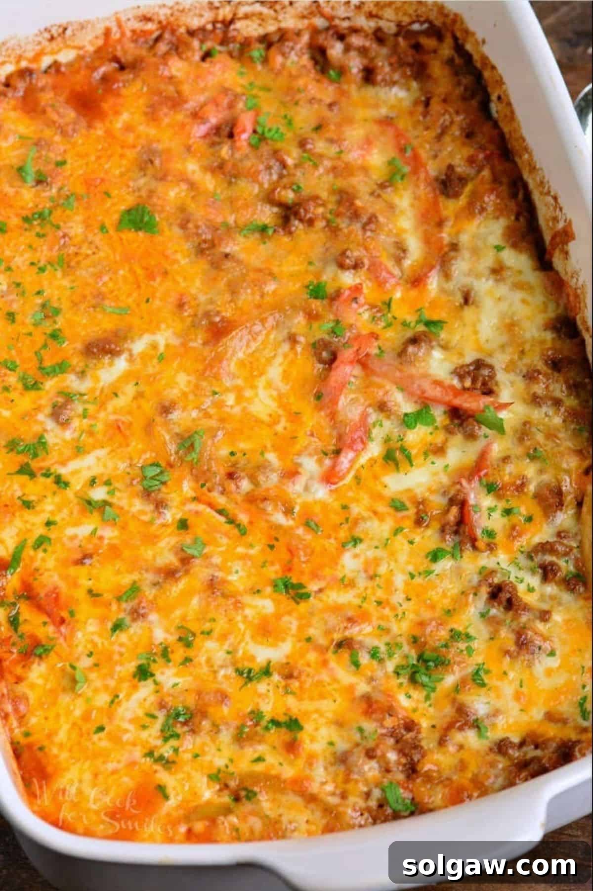 baked enchilada casserole topped with cheese and cilantro on white baking dish.