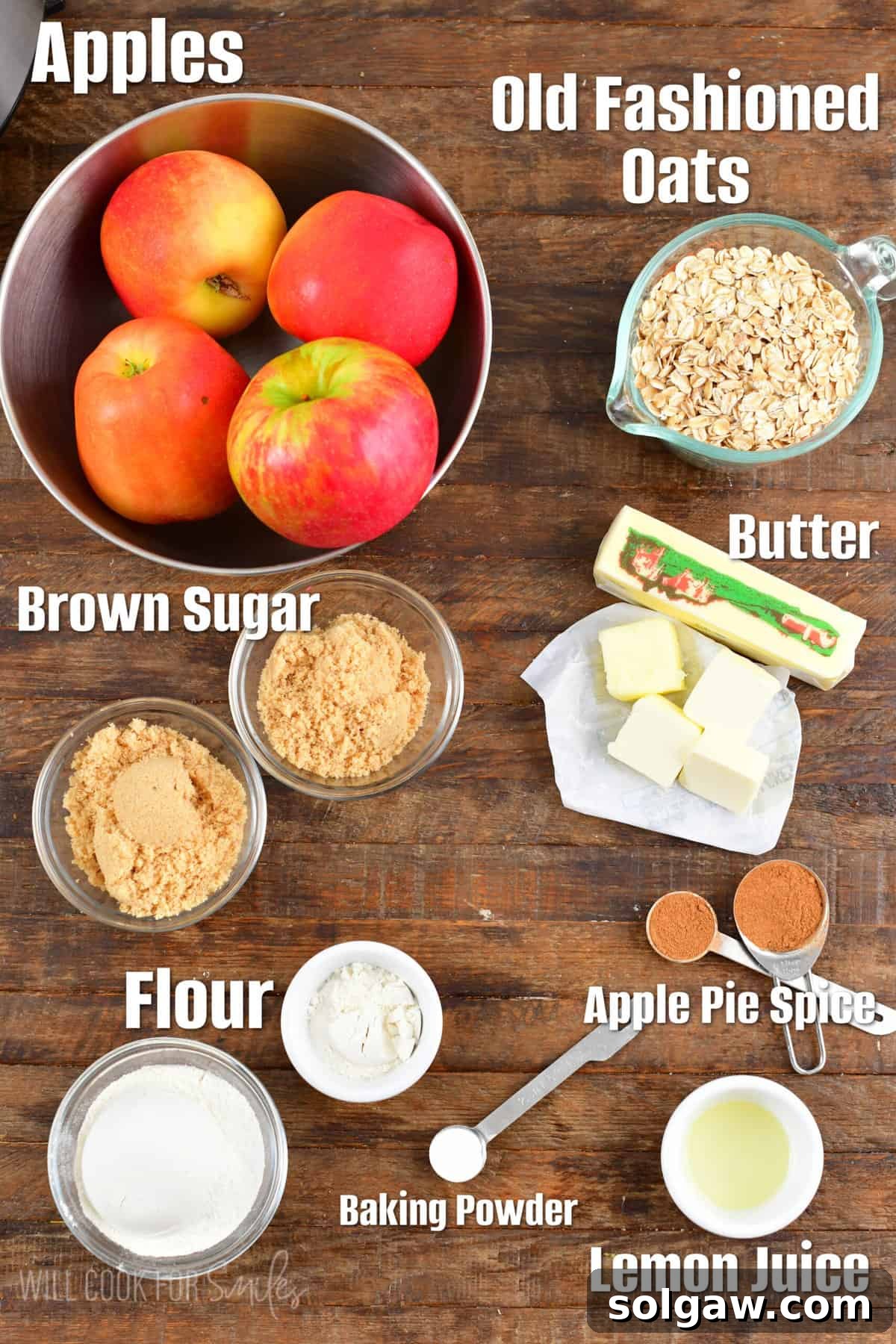 Various ingredients for apple crisp laid out on a wooden surface, including apples, butter, brown sugar, oats, and spices.