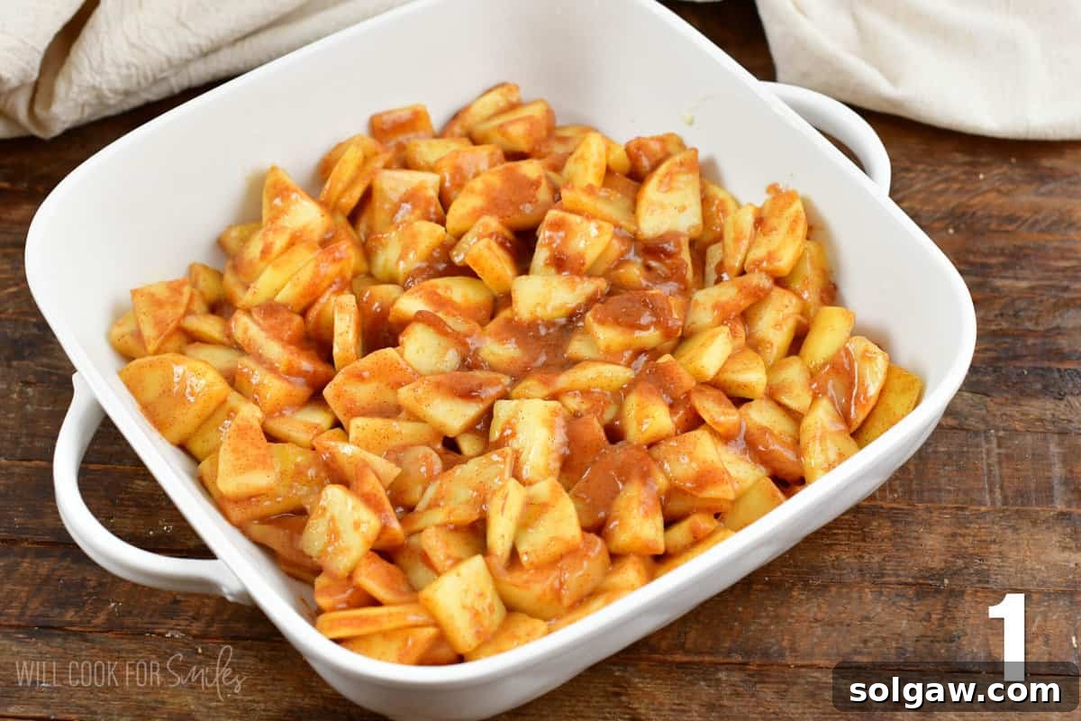 Diced apples mixed with brown sugar and cinnamon in a large casserole dish, ready for baking.