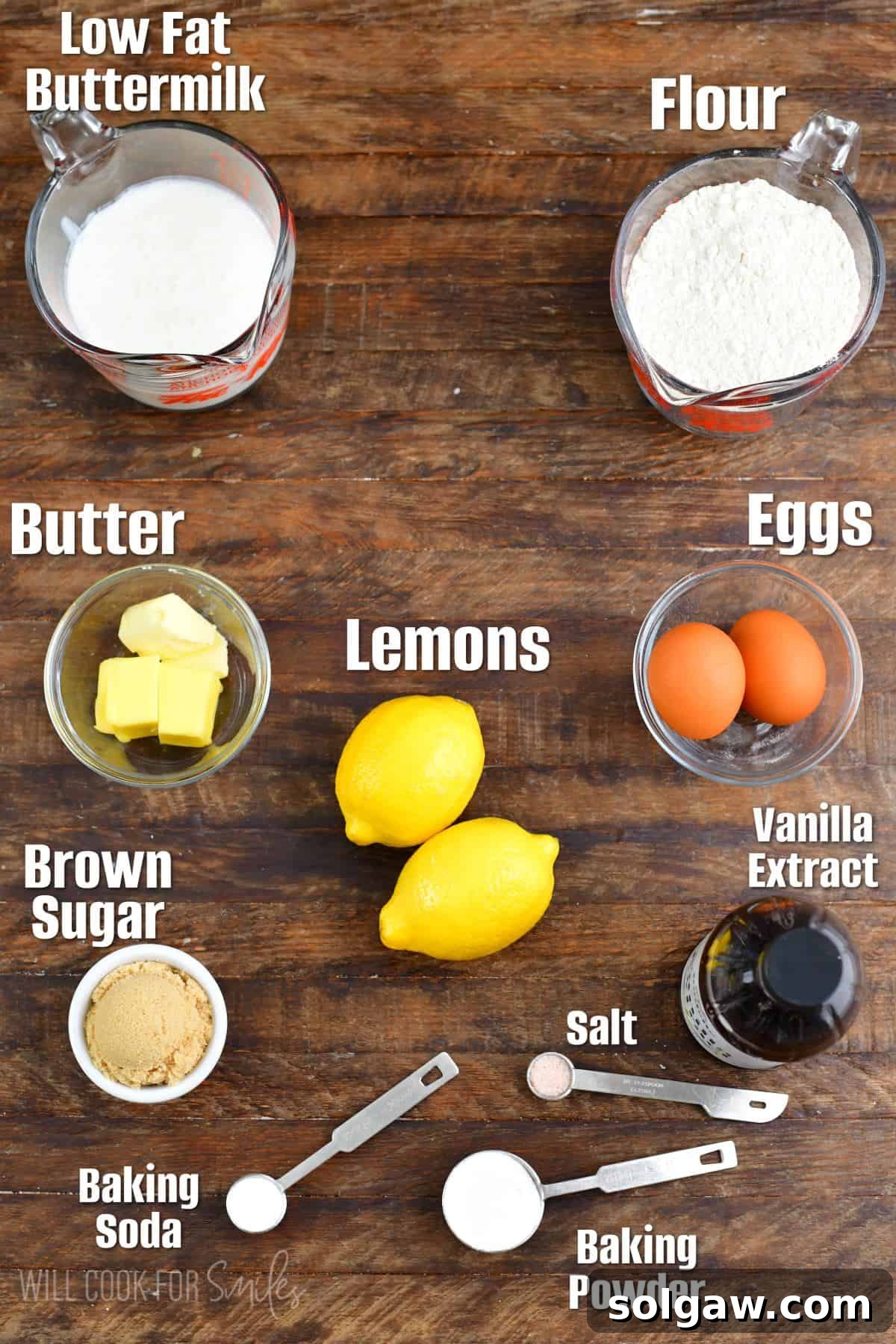 Bright Lemon Pancakes 3 Labeled ingredients for lemon pancakes, neatly arranged on a rustic wooden surface, highlighting fresh lemons, eggs, flour, and buttermilk.