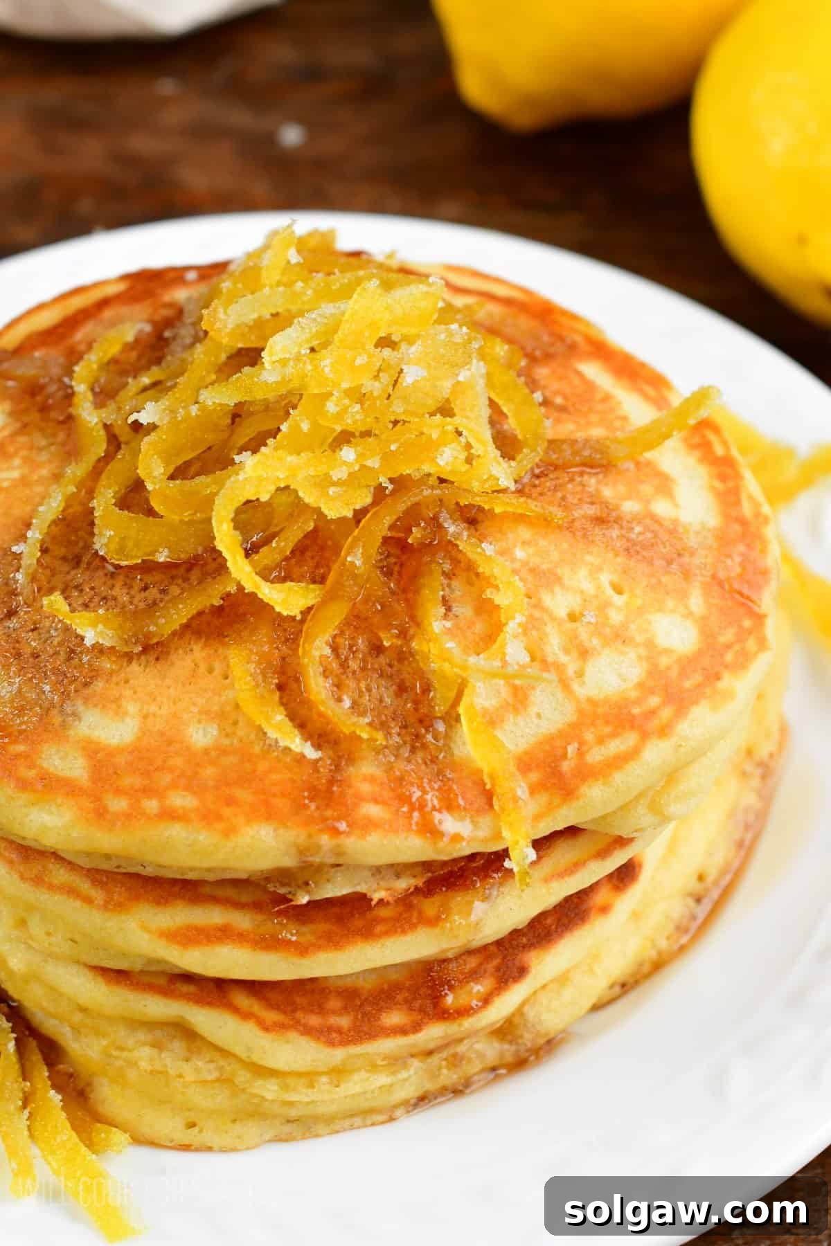 Bright Lemon Pancakes 7 A stack of golden lemon pancakes adorned with delicate lemon peels, ready to be served.