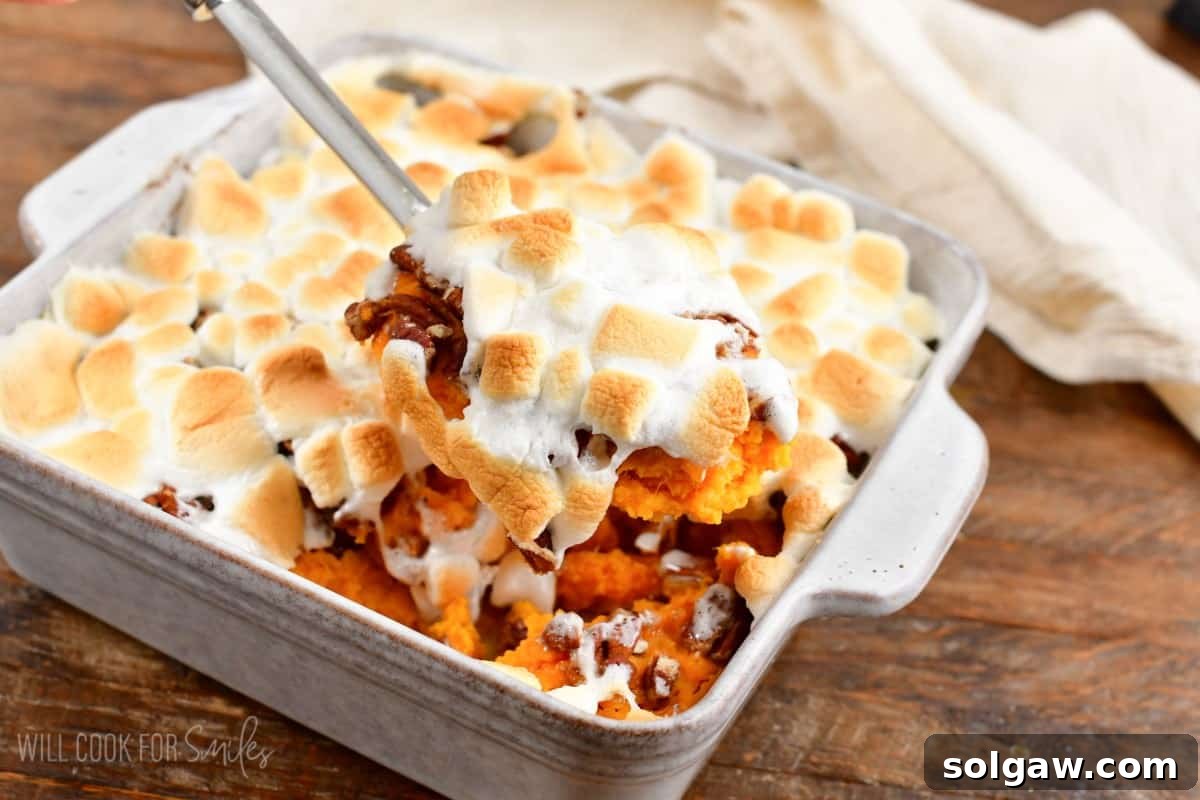 scooping out some sweet potato casserole with marshmallow topping.