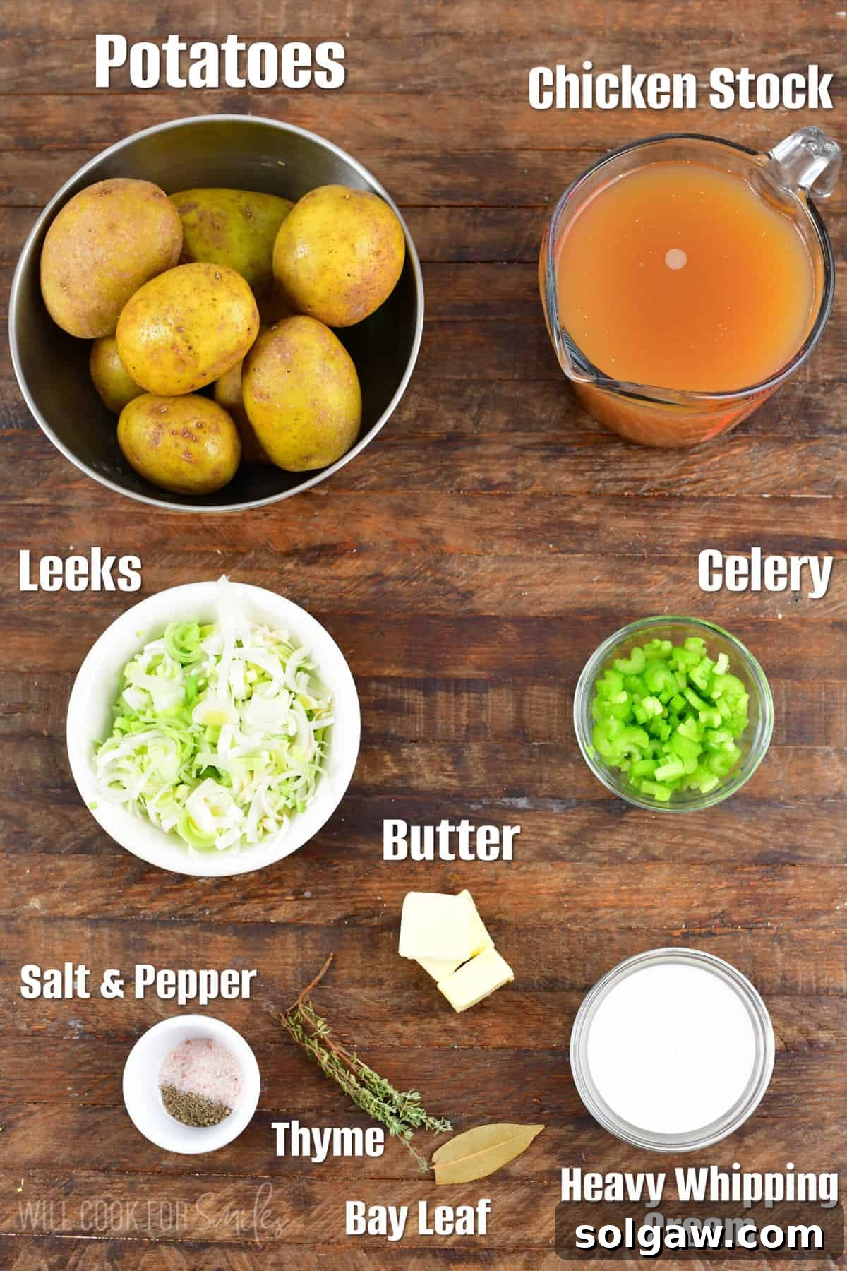 Fresh ingredients for potato leek soup laid out on a rustic wooden surface, including whole leeks, potatoes, celery, and a block of butter.