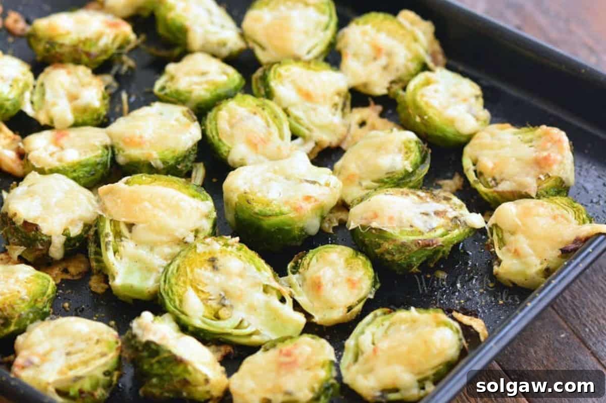 Perfectly roasted Brussels sprouts with golden-brown melted Parmesan cheese on a baking sheet.