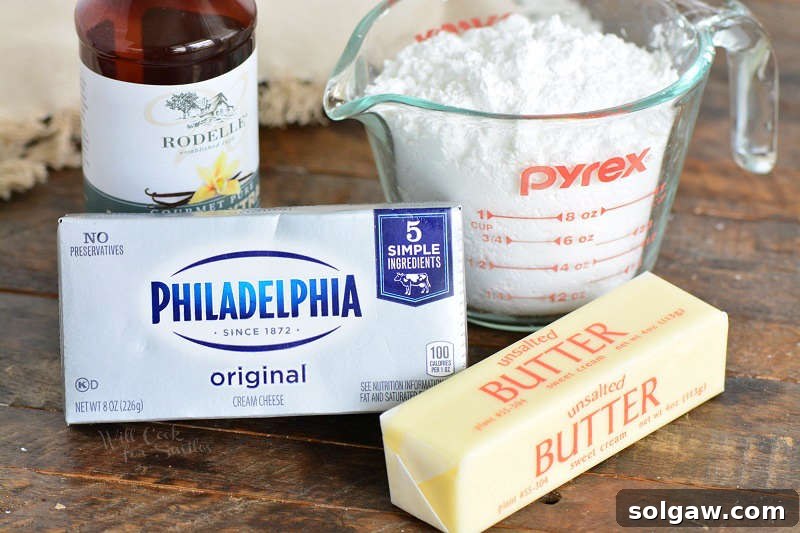 Key ingredients for cream cheese frosting displayed, including butter, cream cheese, powdered sugar, and vanilla extract.
