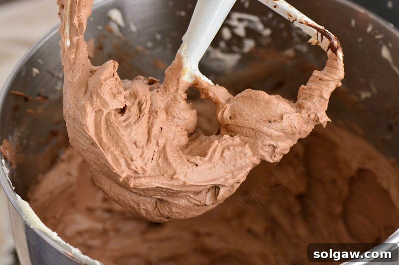 Rich chocolate cream cheese frosting being prepared in a mixer.
