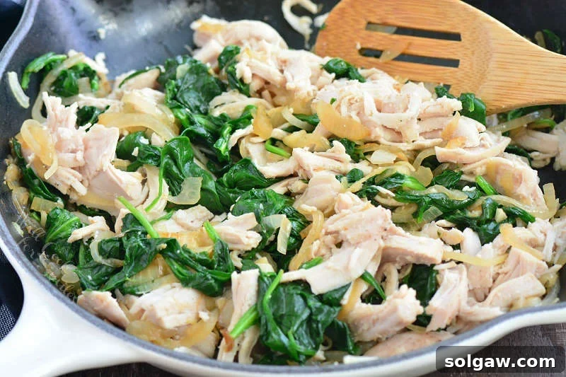 Enchilada filling, a mix of turkey, spinach, and onions, in a cast iron pan