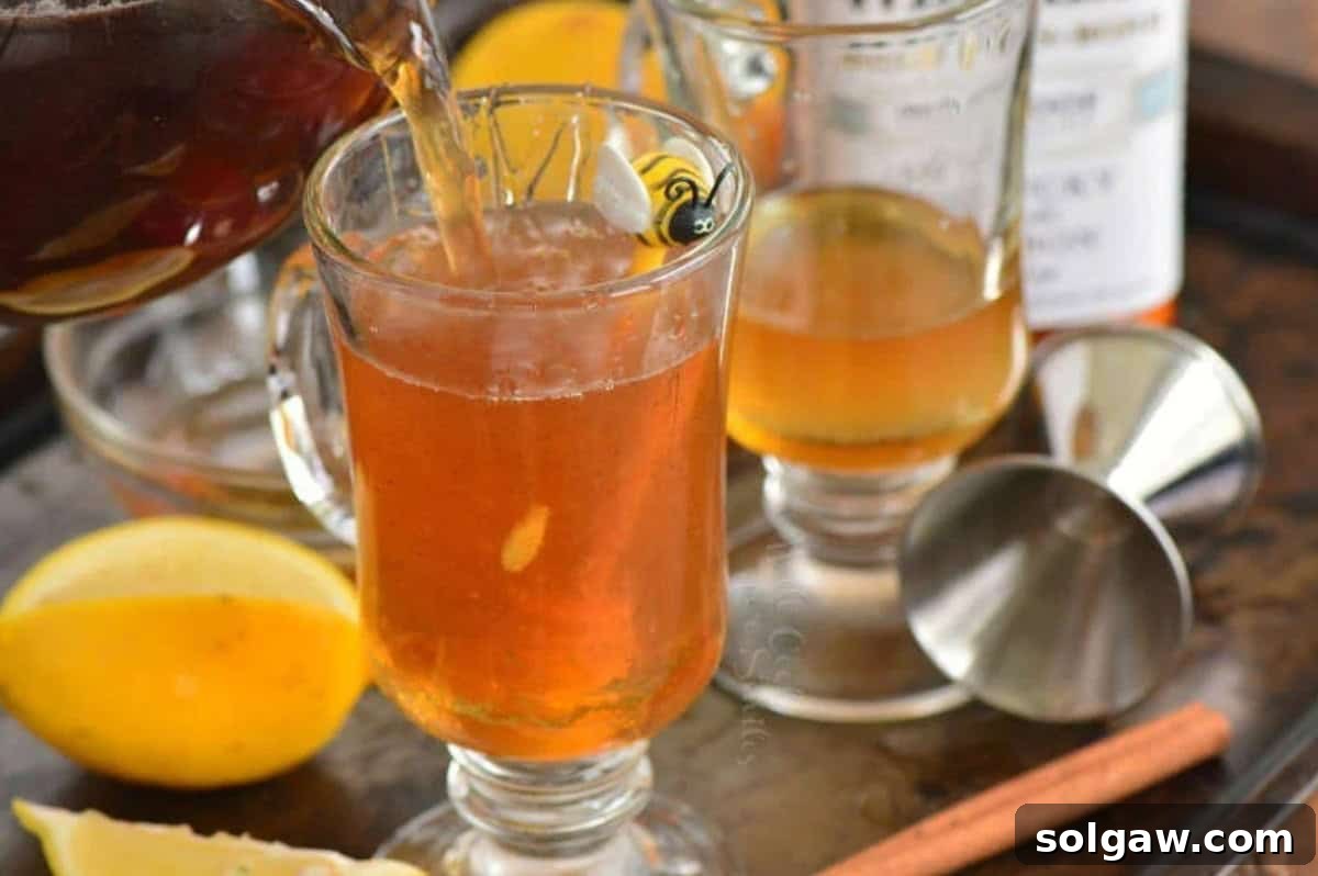 pouring in tea into glass mug to make hot toddy.