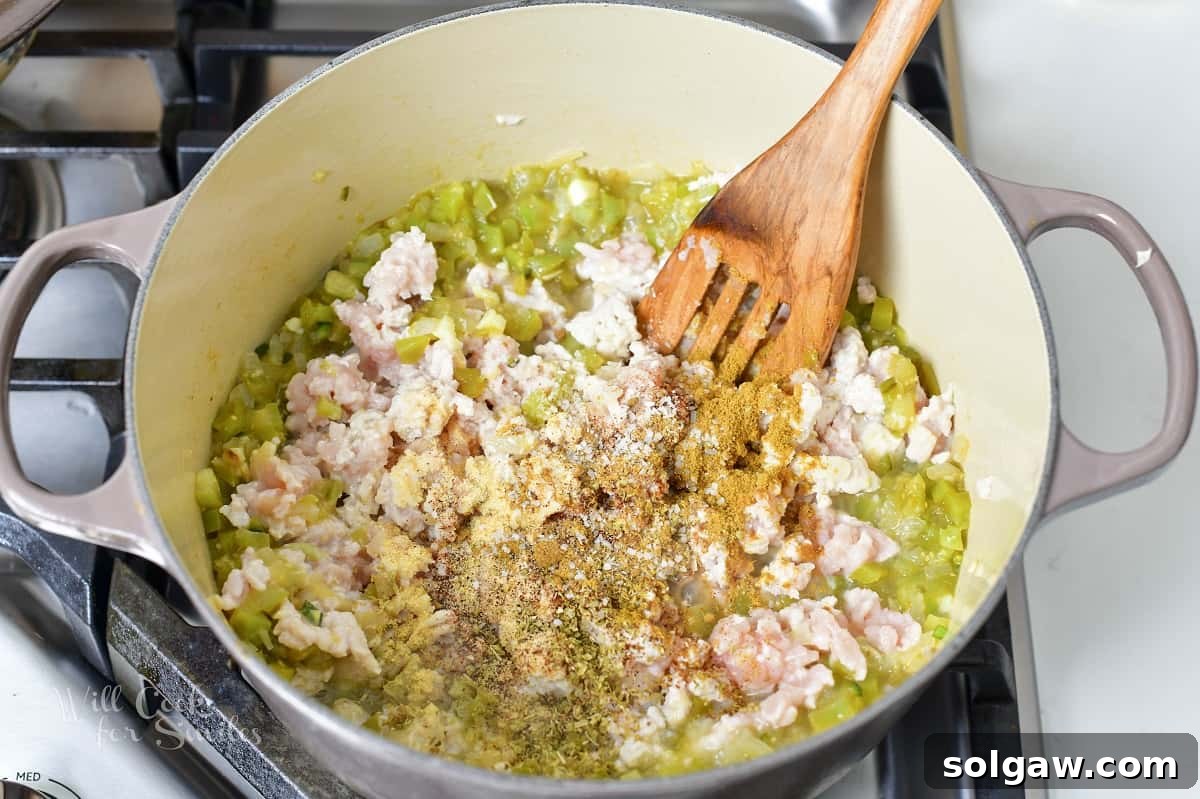 Cooked ground turkey and sautéed vegetables mixed together in a Dutch oven.
